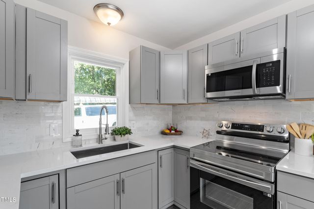 a kitchen with appliances a sink a window and cabinets