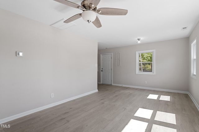 an empty room with a window and a fan