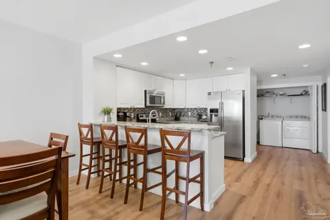 a kitchen with stainless steel appliances kitchen island granite countertop a table chairs stove and white cabinets
