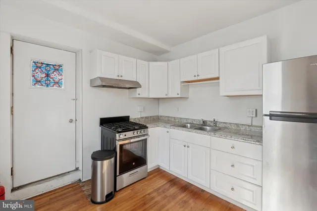 a kitchen with granite countertop a stove a refrigerator and a sink