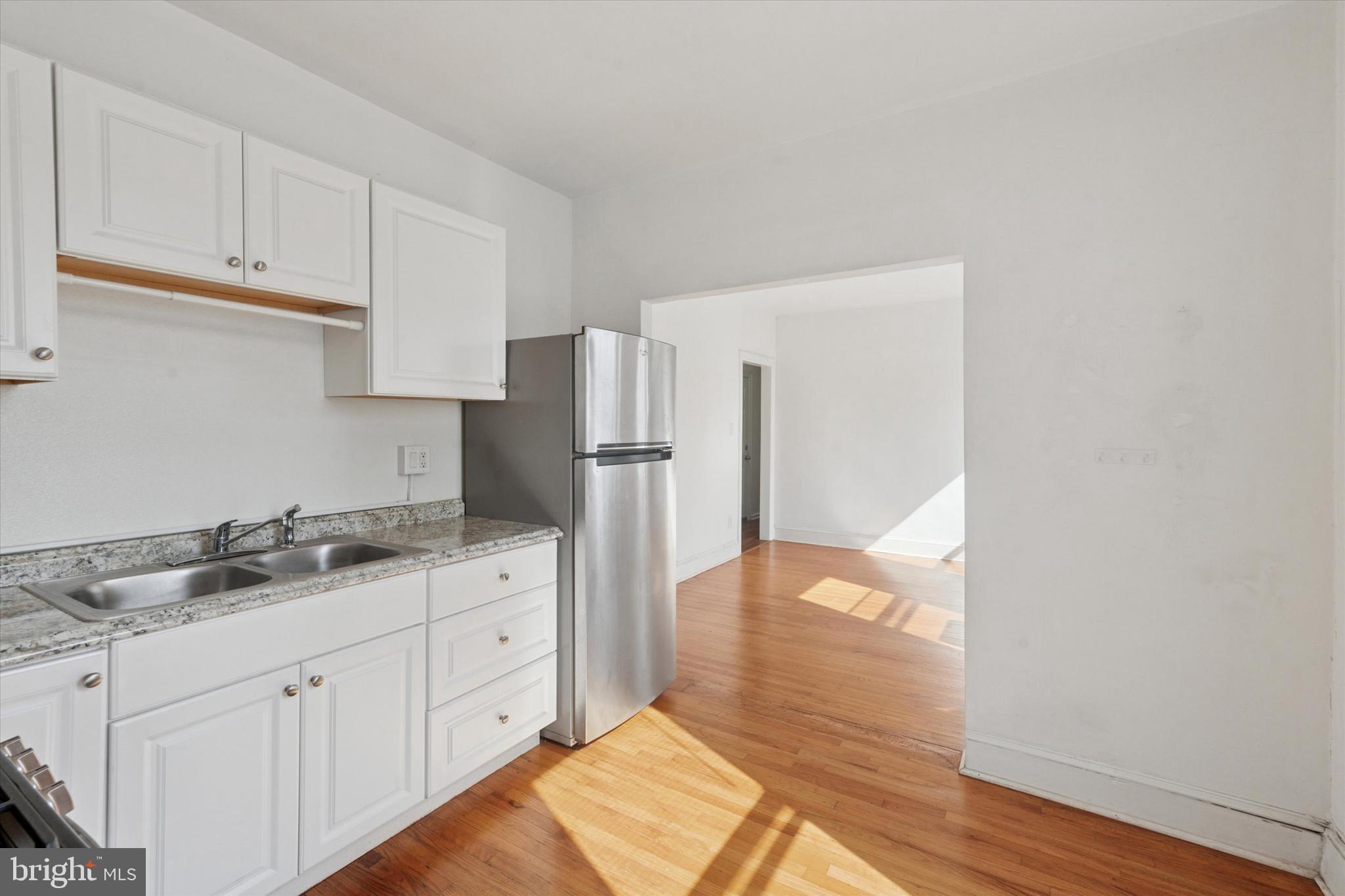1710 South 10th Street, Unit 2 Philadelphia, PA 19148 - Photo 12 of 15 a kitchen with granite countertop a refrigerator and white cabinets