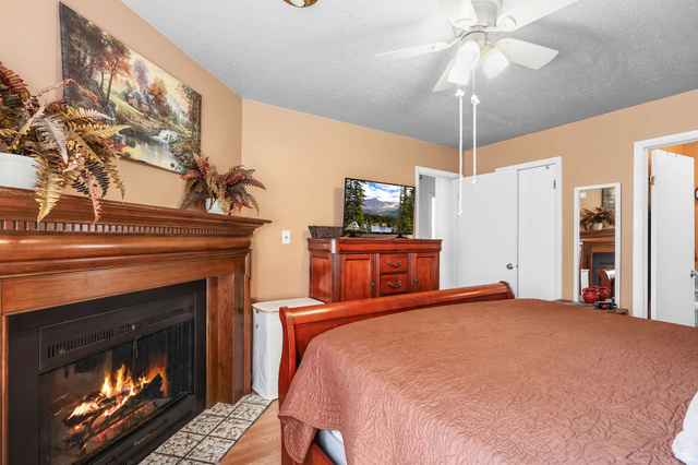 1120 Canyon Road, Unit 38 Ogden, UT 84404 - Photo 15 of 24 Bedroom featuring a fireplace with flush hearth, a textured ceiling, a ceiling fan, and light wood-style floors