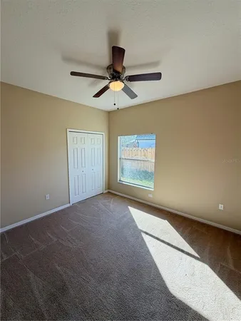 an empty room with windows and fan