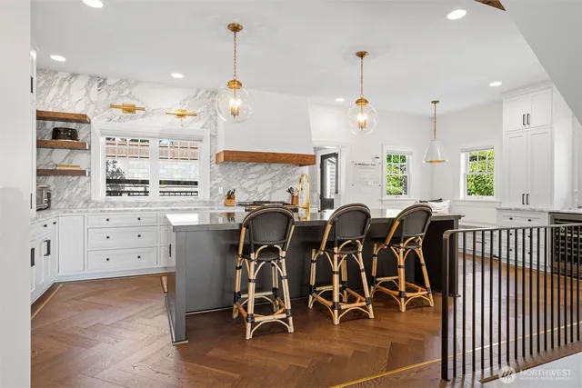 a kitchen with stainless steel appliances kitchen island granite countertop a stove a refrigerator and white cabinets with wooden floor