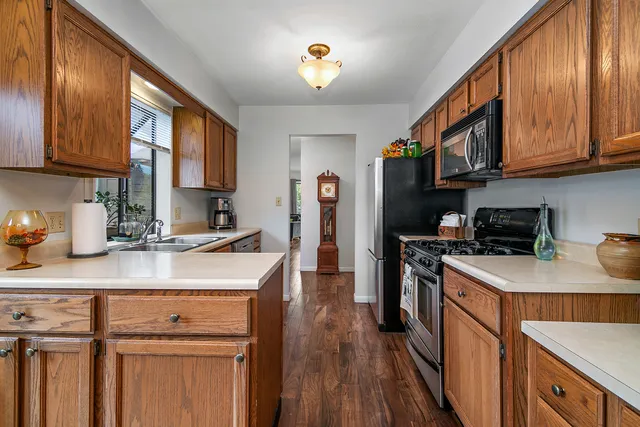 a kitchen with stainless steel appliances granite countertop a stove a sink dishwasher and a refrigerator with wooden floor