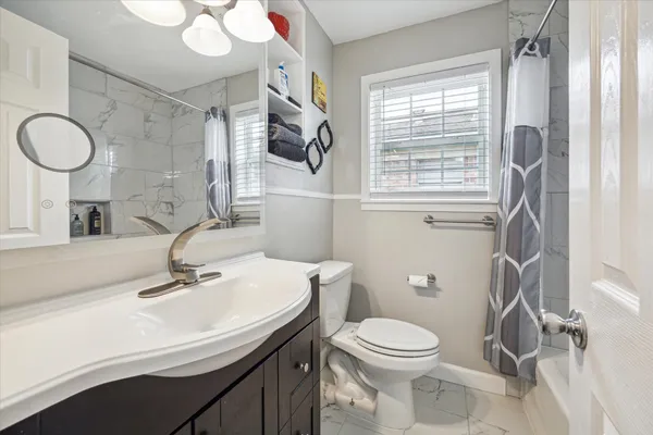 a bathroom with a sink a toilet a mirror and a window