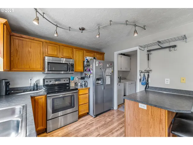 a kitchen with stainless steel appliances granite countertop a sink refrigerator stove and microwave