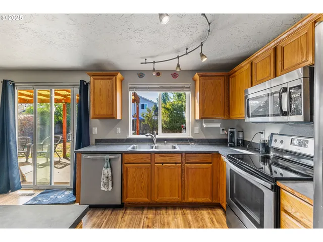 a kitchen with stainless steel appliances granite countertop a sink window and cabinets