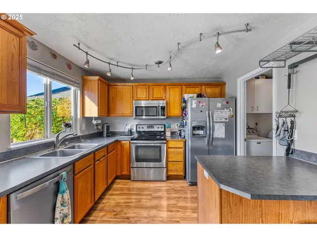 a room with stainless steel appliances wooden floors and large windows