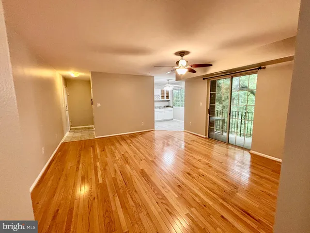 a view of empty room with wooden floor and fan