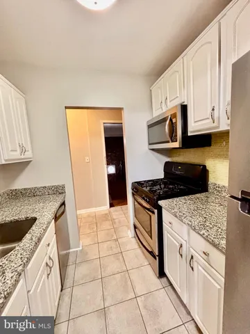 a kitchen with stainless steel appliances granite countertop a stove a sink and a white cabinets