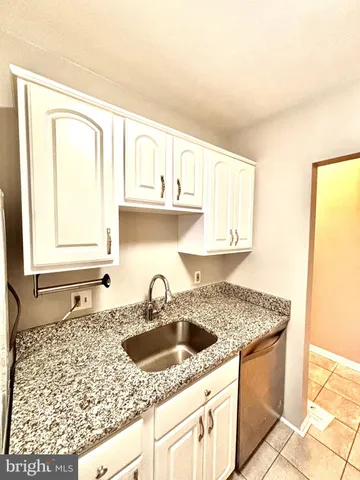 a kitchen with granite countertop a sink a stove and cabinets