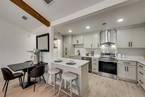 a kitchen with a stove a sink and white cabinets