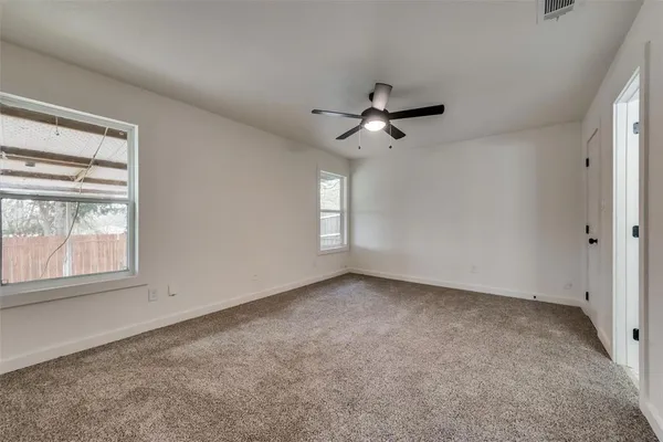 an empty room with windows and fan
