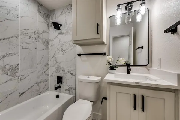 a bathroom with a granite countertop toilet sink and mirror