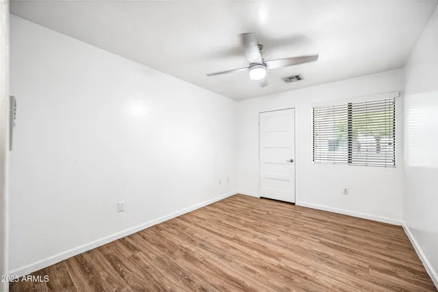 a view of empty room with wooden floor and fan