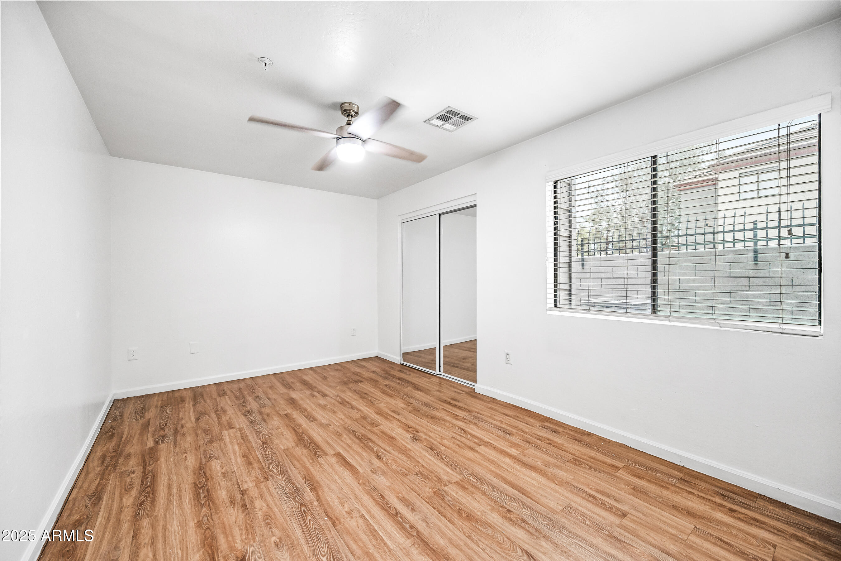 3065 North 67th Avenue, Unit 135 Phoenix, AZ 85033 - Photo 16 of 30 a view of empty room with wooden floor and fan