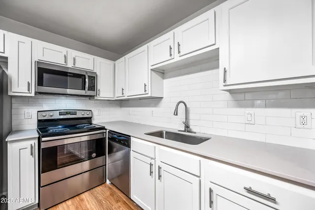 a hall with kitchen island white cabinets and wooden floor