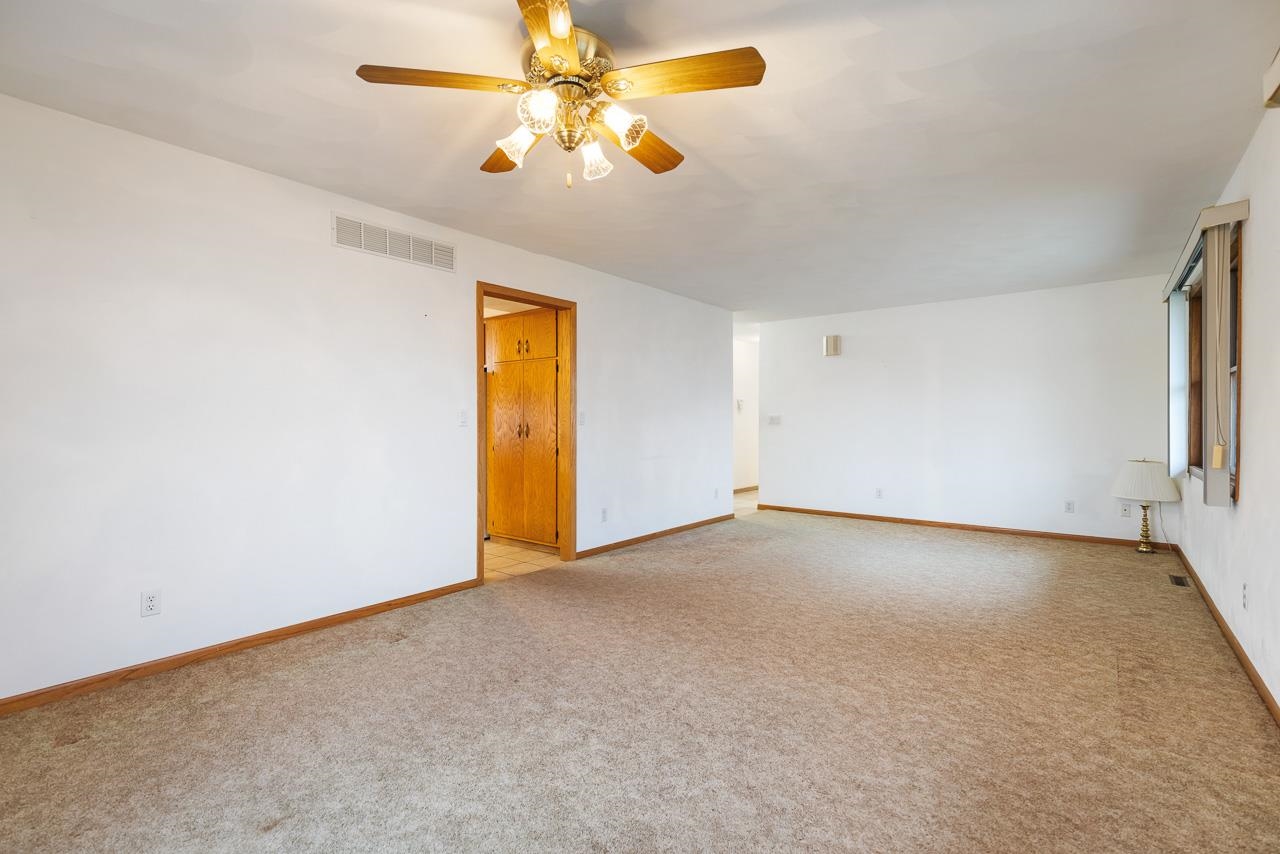 3178 North Berlin School Road Ridott, IL 61067 - Photo 18 of 47 an empty room with a chandelier fan and windows