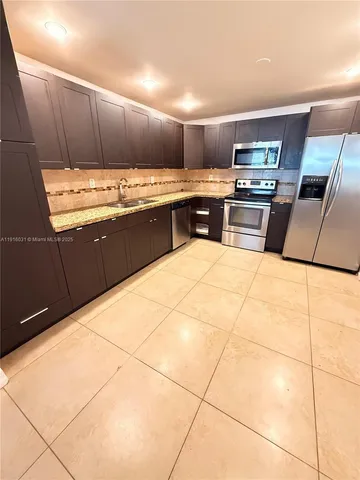 a kitchen with stainless steel appliances kitchen island granite countertop a sink counter space cabinets and appliances
