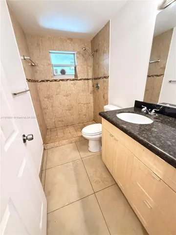 a bathroom with a granite countertop sink a toilet a mirror and vanity