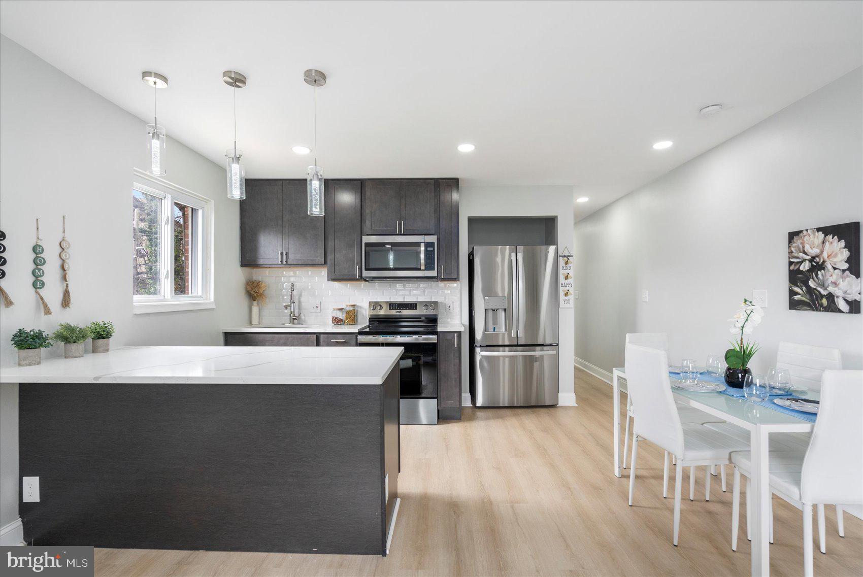 4002 Derby Manor Drive Baltimore, MD 21215 - Photo 8 of 32 a kitchen with stainless steel appliances kitchen island granite countertop a refrigerator a stove a sink a dining table and chairs