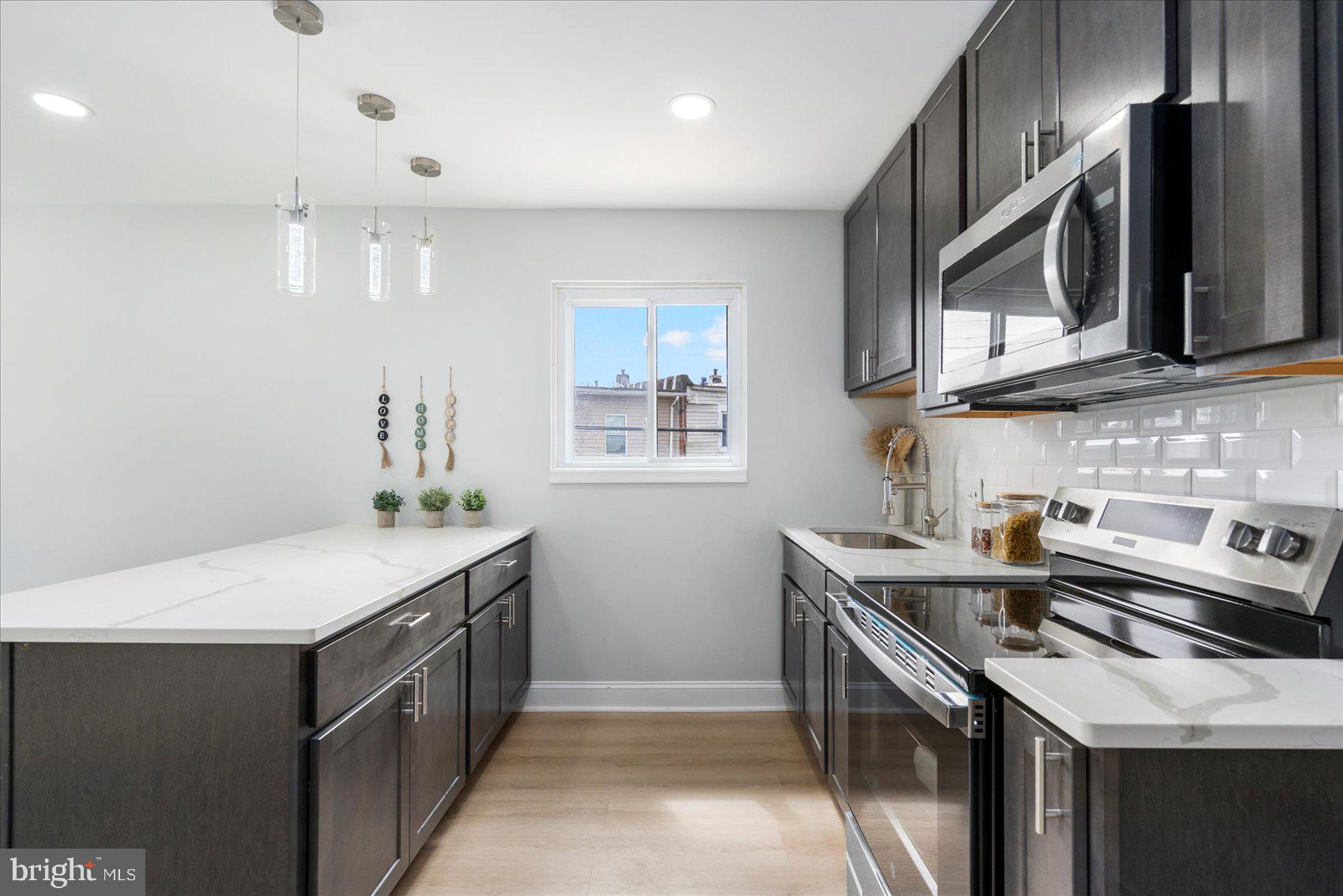 4002 Derby Manor Drive Baltimore, MD 21215 - Photo 9 of 32 a kitchen with stainless steel appliances granite countertop a sink stove and microwave