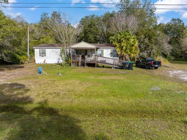 a yellow house sitting in middle of the middle of a yard