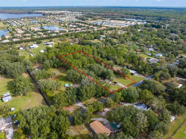 an aerial view of residential houses with outdoor space and trees