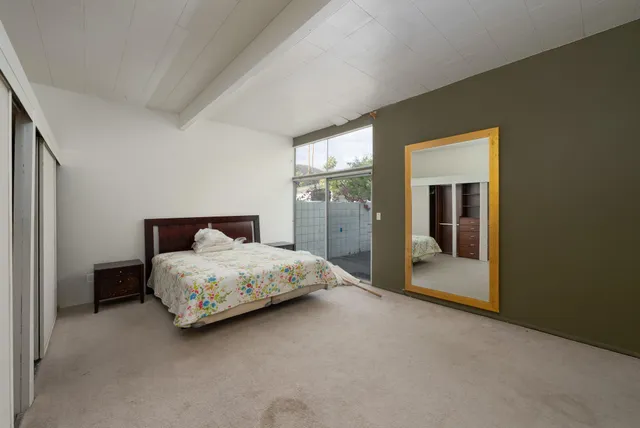 a bedroom with a bed and large mirror