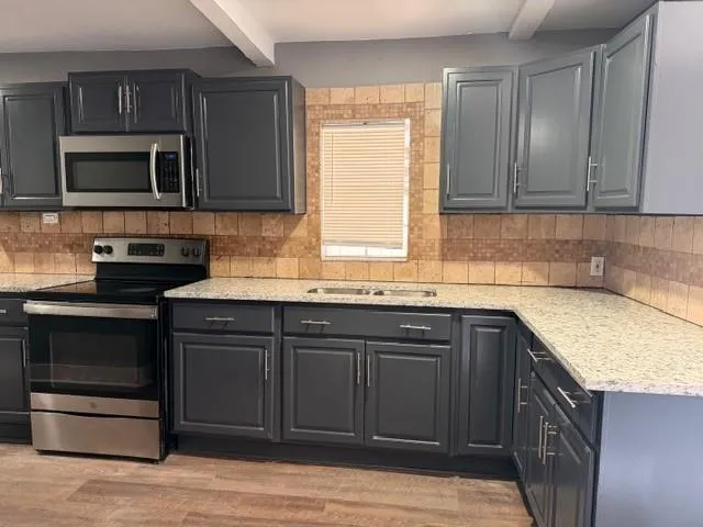 a kitchen with stainless steel appliances granite countertop a sink stove and microwave