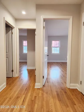 a view of a hallway with wooden floor and a bathroom