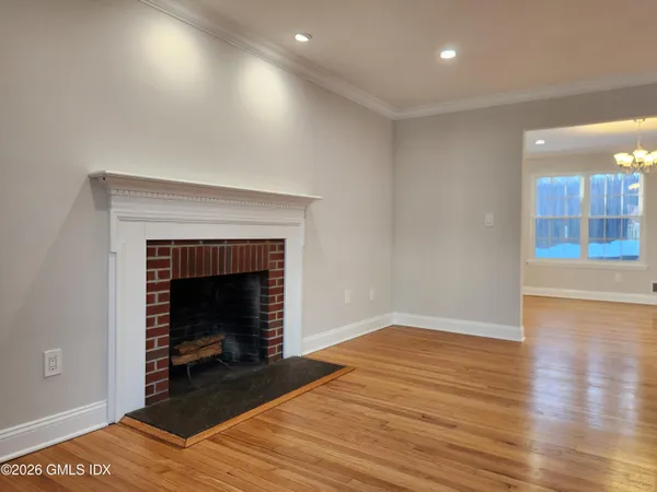 a view of an empty room with wooden floor fireplace and a window