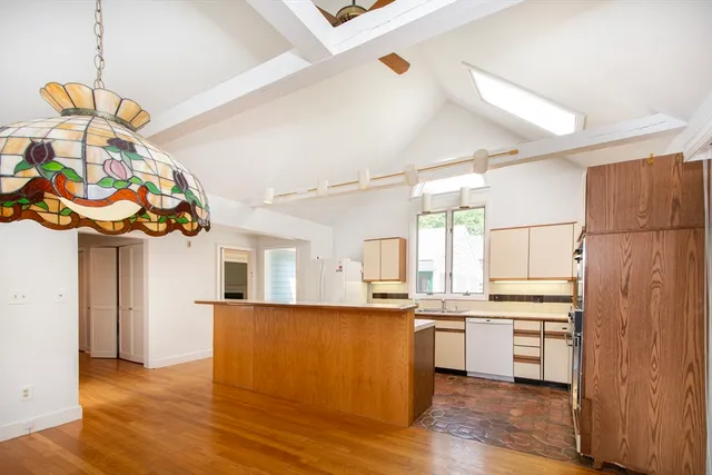 a kitchen with stainless steel appliances granite countertop a refrigerator a oven a sink and white cabinets with wooden floor