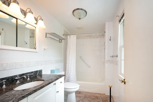a bathroom with a granite countertop sink toilet and shower
