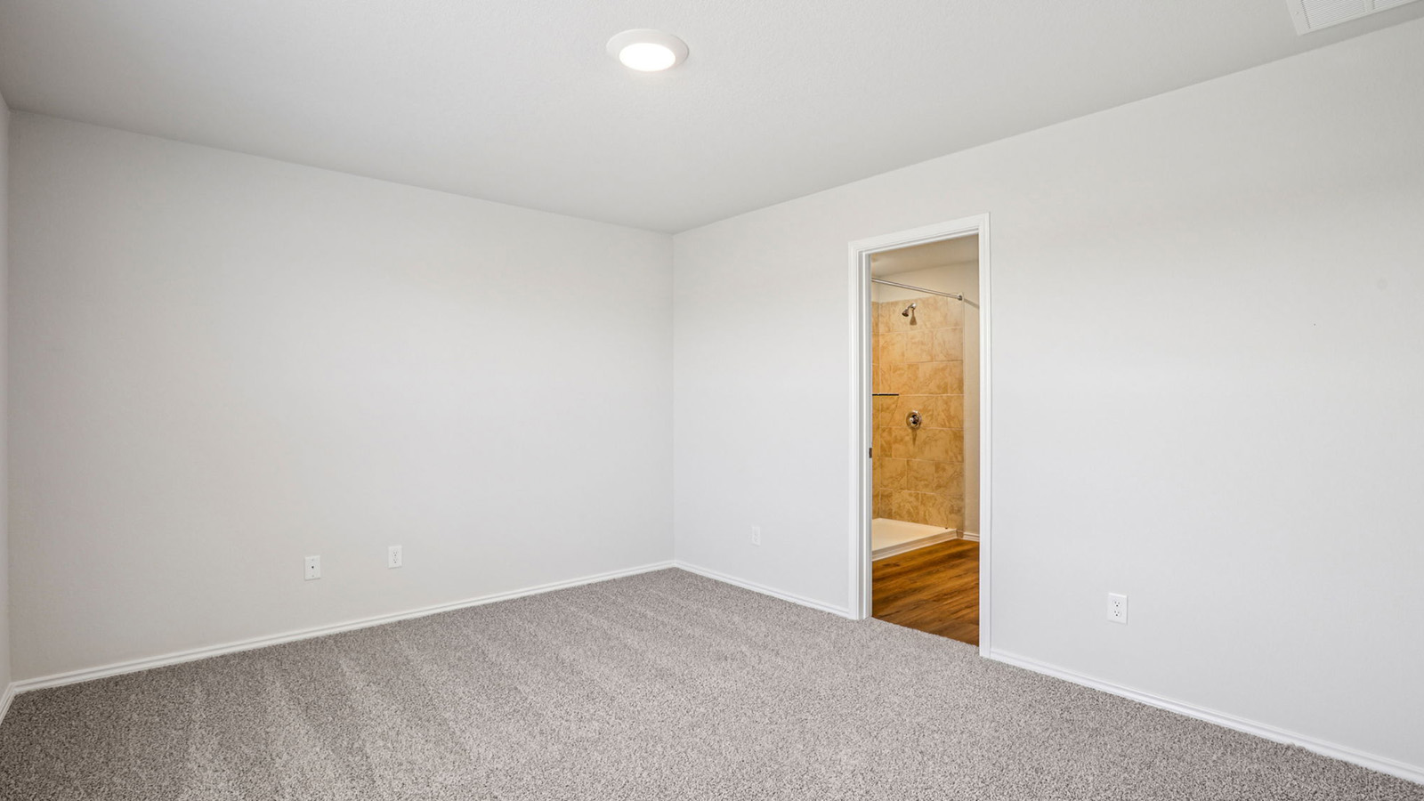 148 Wyatt Way Jarrell, TX 76537 - Photo 18 of 33 Carpeted room featuring a recessed ceiling light and an entryway to a full bathroom with a tiled shower and wood-finish flooring