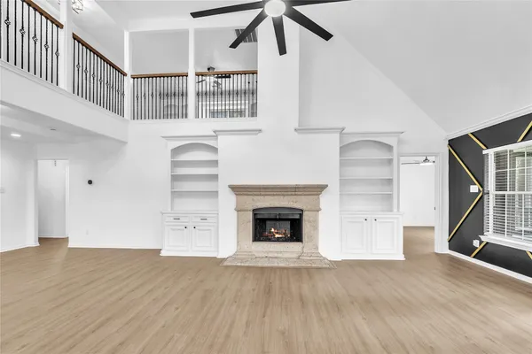 a view of an empty room with wooden floor fireplace and a window
