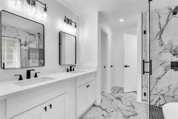 a bathroom with double vanity sinks a toilet a mirror and shower