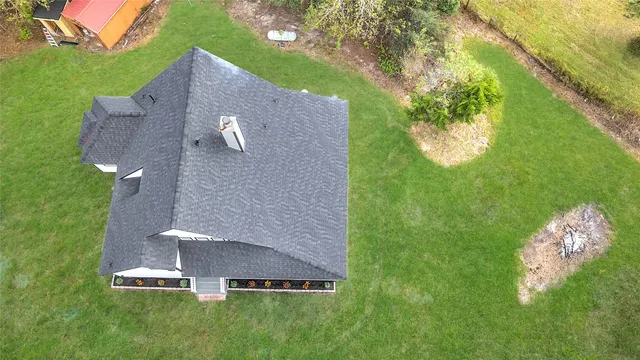 an aerial view of a house with a yard and trees all around