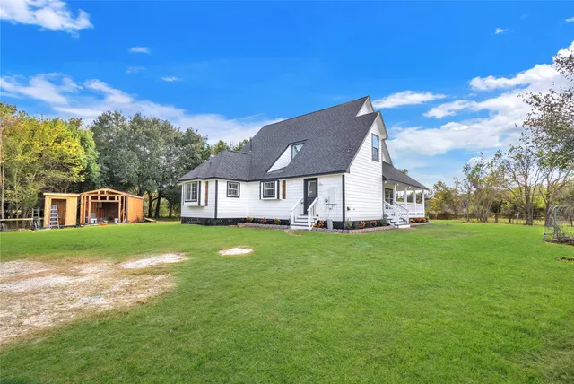 a view of a house with a big yard plants and large trees