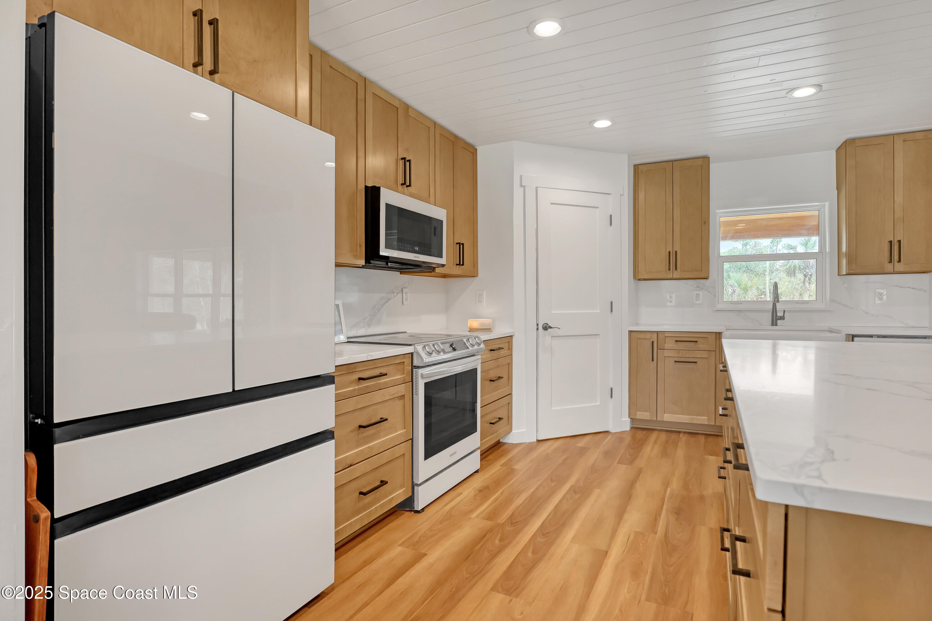3350 Leghorn Road Malabar, FL 32950 - Photo 54 of 55 a kitchen with stainless steel appliances a stove a microwave and white cabinets