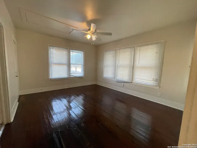 a view of an empty room with wooden floor and a window