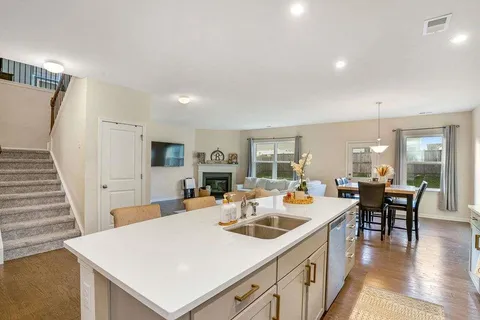 a large white kitchen with sink a refrigerator and chairs