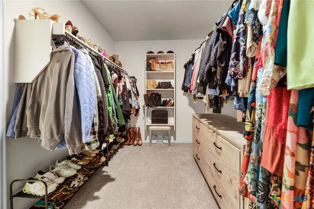 a view of walk in closet with clothes and shoes