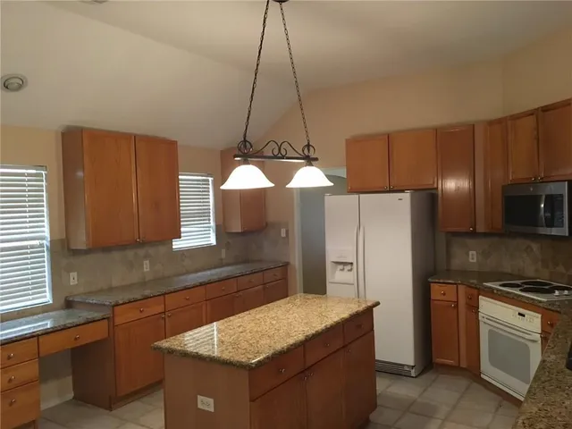 a kitchen with stainless steel appliances granite countertop a sink a stove a refrigerator a washer and dryer