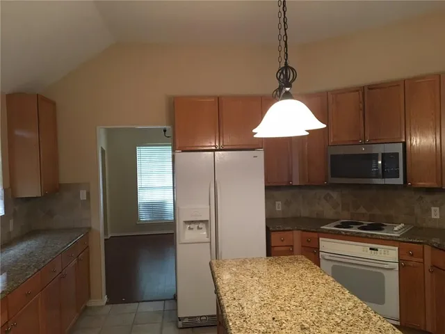 a kitchen with stainless steel appliances granite countertop a refrigerator and a sink