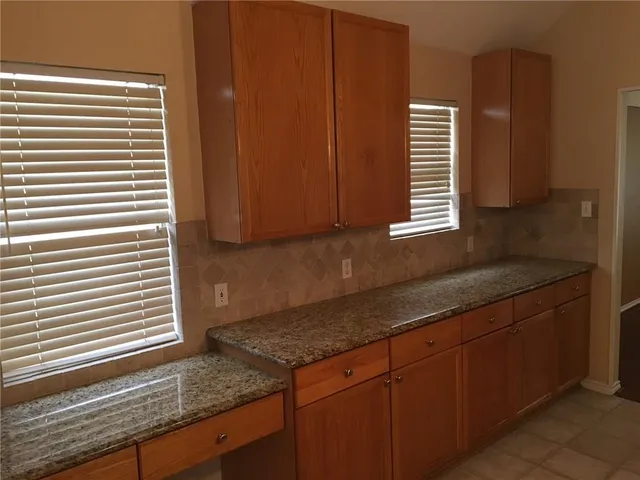 a kitchen with granite countertop cabinets and window
