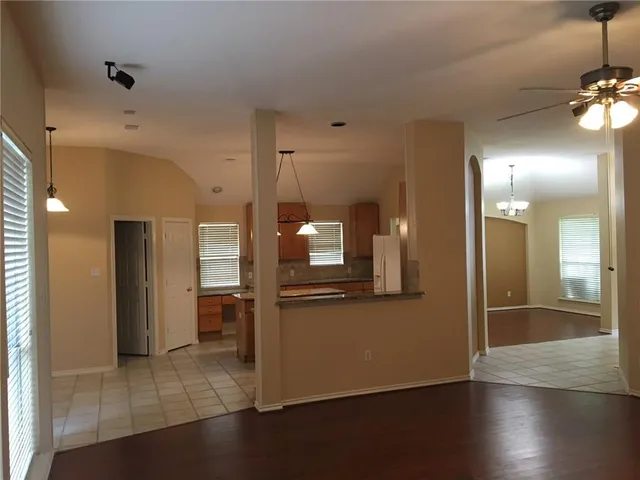 an empty room with wooden floor and kitchen view