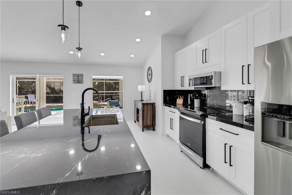 172 Plantation Circle Naples, FL 34104 - Photo 6 of 36 a kitchen with stainless steel appliances granite countertop a sink a stove and cabinets