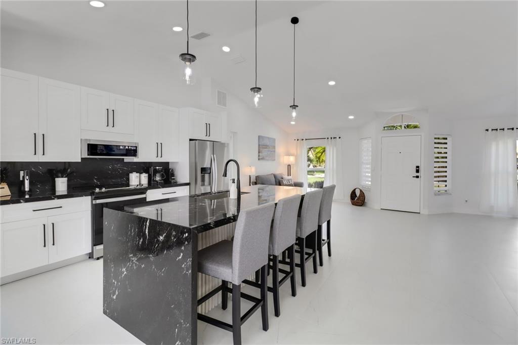 172 Plantation Circle Naples, FL 34104 - Photo 36 of 36 a kitchen with stainless steel appliances kitchen island granite countertop a stove a sink a dining table and chairs with white cabinets